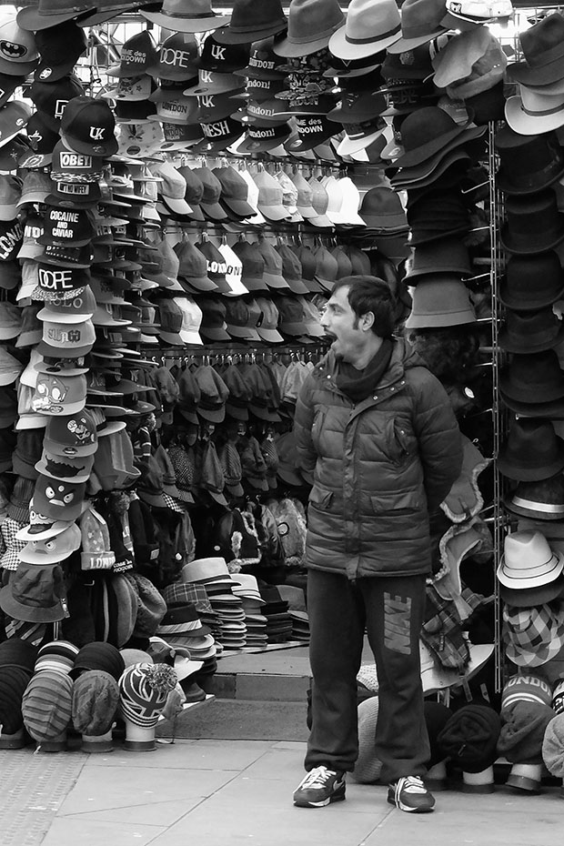 © Neil Turner, January 2014. Bored shop keeper outside his open hat shop just outside one of main areas of Camden Market