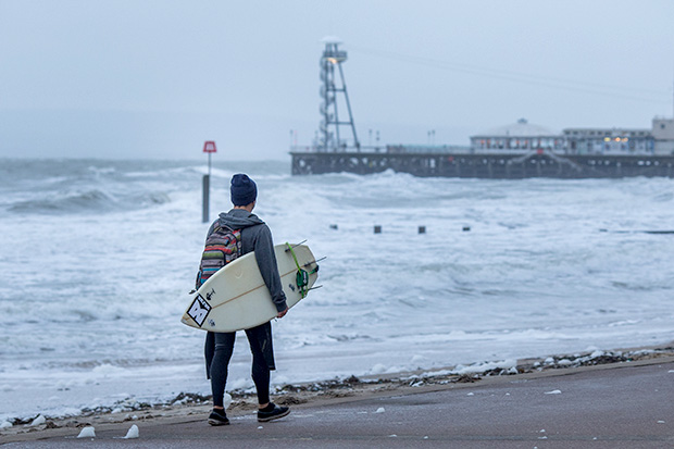 ©Neil Turner, November 2014. Surfer heads towards Bournemouth Pier as the waves get bigger during a storm.