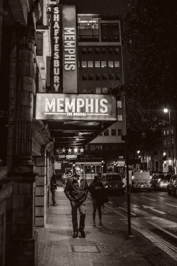 Pedestrian passes under the "Memphis" banner outside a west end theatre at night. © Neil Turner November 2014.