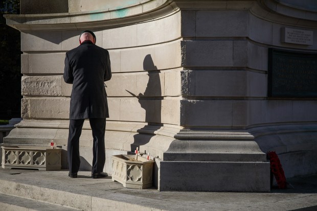 Mark Tapping who served 27 years in the Royal Marines places a framed photograph of his relative Royal Marine Musician Albert Pike who died when HMS Hood was sunk on the 24th of May 1941. Armistice Day at the War Memorial in Bournemouth 11 November 2016. Bournemouth, United Kingdom. Photo: Neil Turner